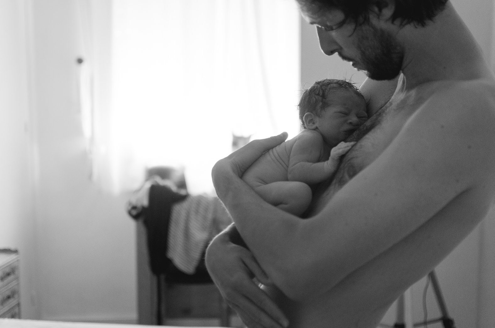Fotógrafa de partos Un padre sosteniendo a su bebé recién nacidda